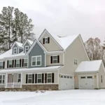 Large home with off-white siding covered with snow